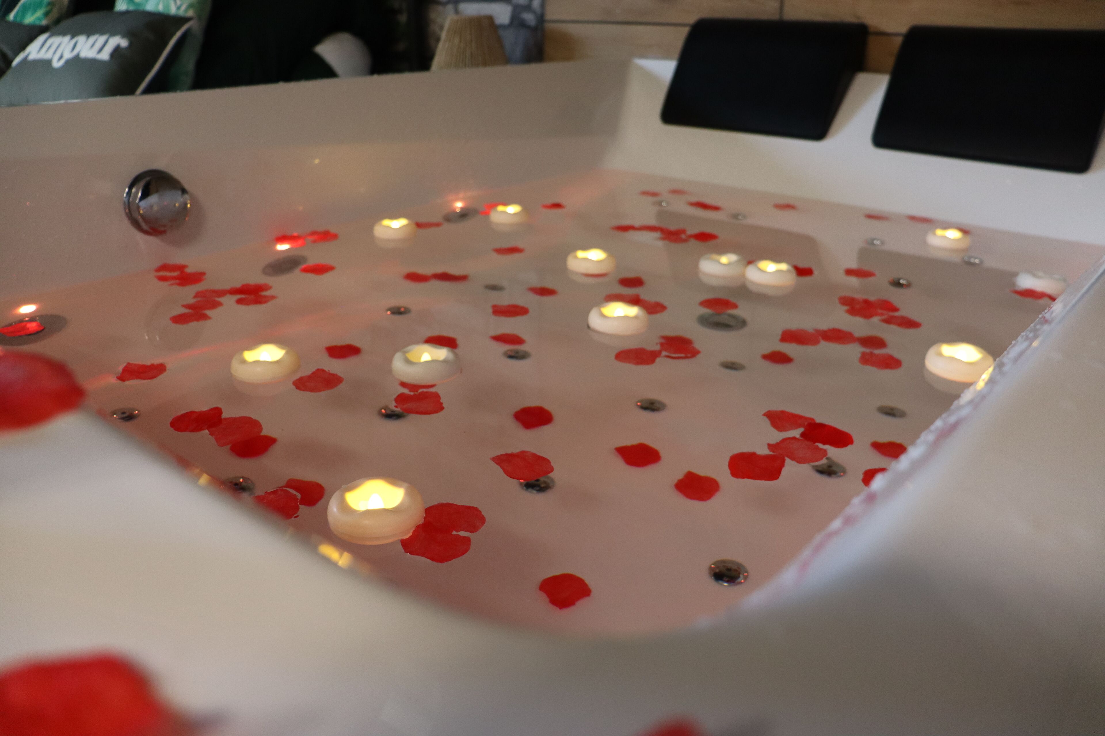 Et badekar med stearinlys og rosenblade.