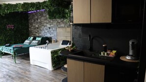A modern kitchen with a stone wall, wooden cabinets, and a black countertop. - Jung'Love room - Spa & Private Cinema (Saint-Cyprien)