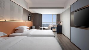 A hotel room with two beds, a small table, a chair, a TV, and a large window with a city view. - Days Inn By Wyndham Zhengzhou Xinzheng Airport (Zhengzhou)