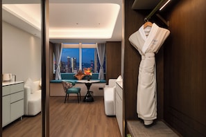 Une chambre d’hôtel avec vue sur la ville, un coin repas avec une table et des chaises, et un peignoir accroché au mur.
