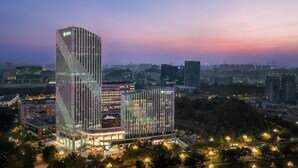 Un hotel moderno con un diseño vertical llamativo, varios pisos y una entrada destacada.