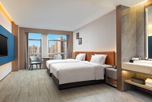 Une chambre d’hôtel équipée d’un lit, d’un bureau, d’une chaise, d’une télévision et d’une salle de bain avec un miroir.