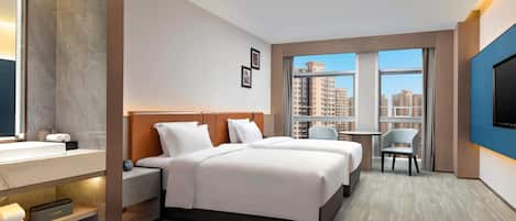 A hotel room with a bed, bedside tables, a TV, a small desk, and a window with a city view.