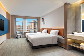 A hotel room with a bed, a desk, a chair, a TV, and a bathroom with a mirror. - Wyndham Garden Changsha Economic Development Zone (Changsha)