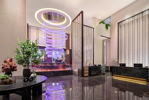 A modern lobby with a central spiral light installation, a reception desk, and a seating area with a fire feature. - Wyndham Garden Changsha Economic Development Zone (Changsha)