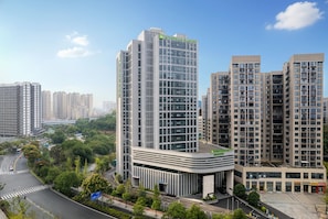 A high-rise building with a modern glass facade, surrounded by other residential buildings and a green park area. - Wyndham Garden Changsha Economic Development Zone (Changsha)