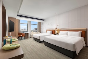Une chambre d’hôtel avec deux lits, un bureau, une chaise, une télévision et une vue sur la ville.