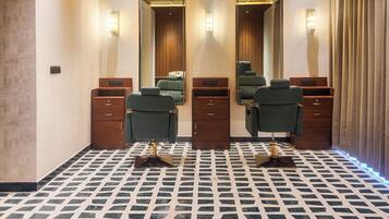 A room with two mirrors, a green salon chair, wooden cabinets, and a patterned floor.