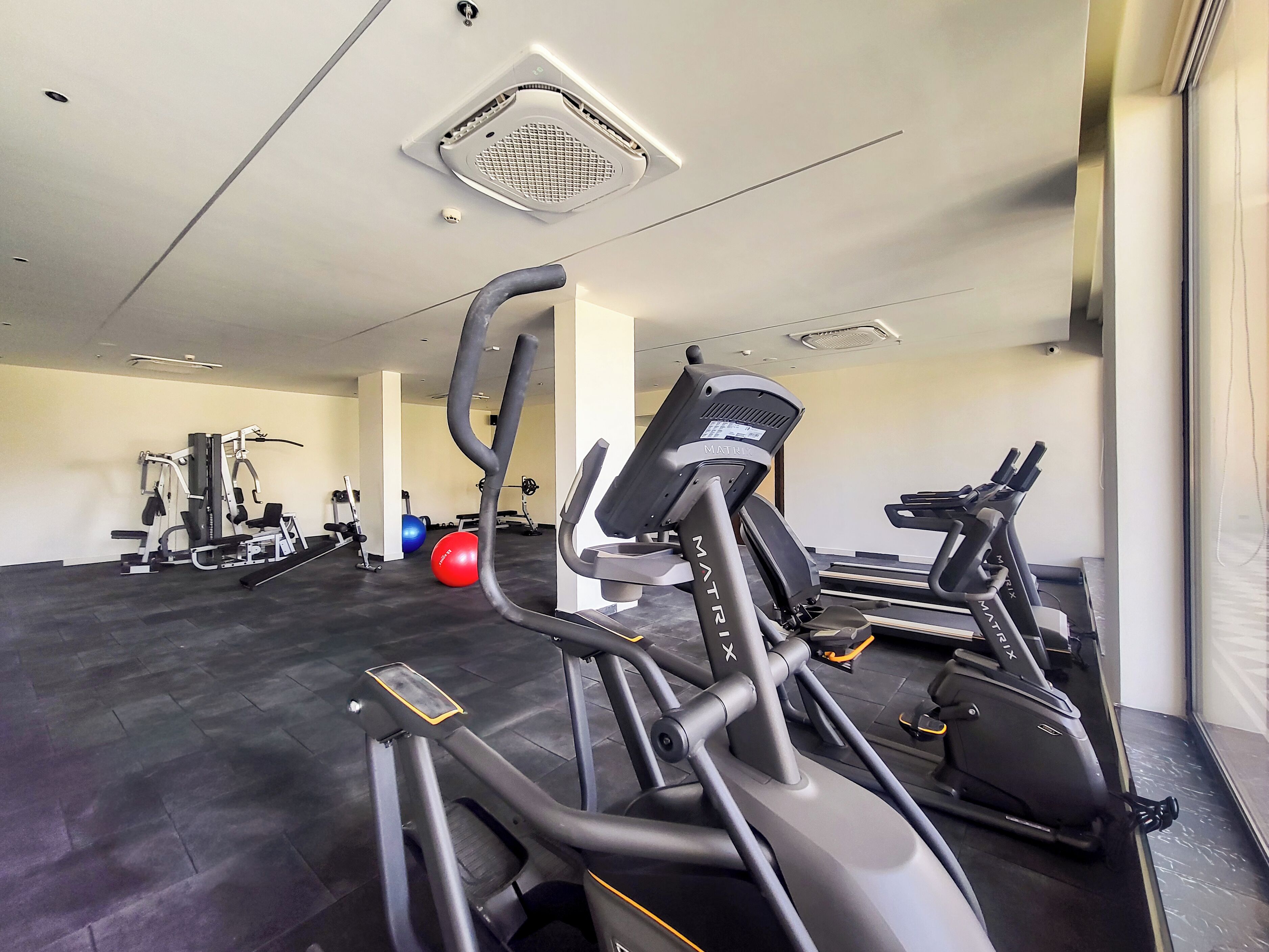 Un gimnasio con cintas de correr, elípticas y pelotas de ejercicios.