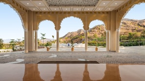 Un espacio al aire libre techado con arcos, columnas y vistas a un paisaje montañoso.