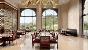 A spacious dining area with high ceilings, large windows, and a view of the outdoors. - Wyndham Garden Udaipur Bhuwana (Udaipur)