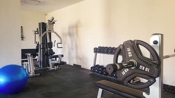 Ein Fitnessraum mit Gewichthebereien, einer Hantelbank und einem blauen Trainingsball.