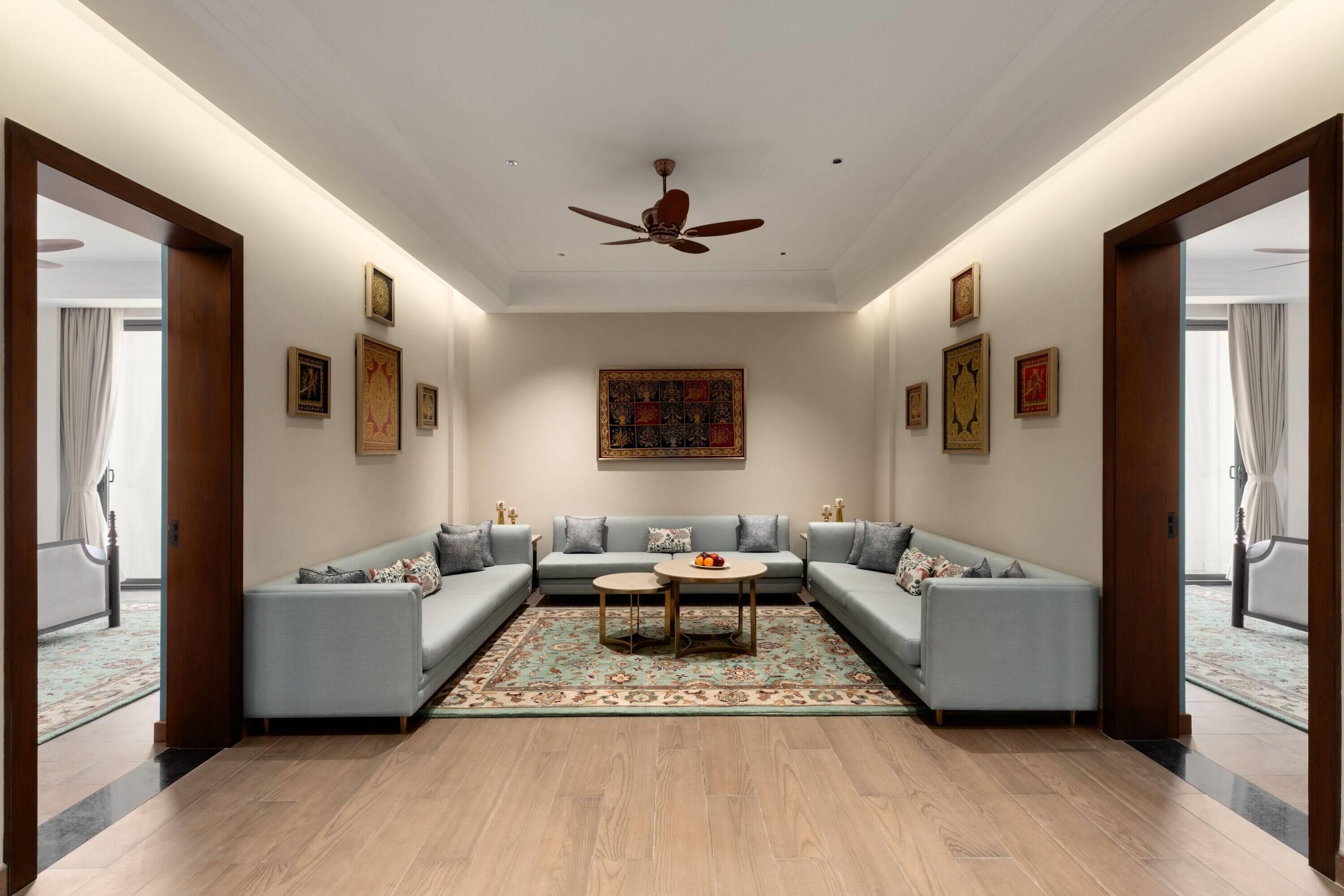 Un salón amplio con un sofá modular, un ventilador de techo y una alfombra grande.