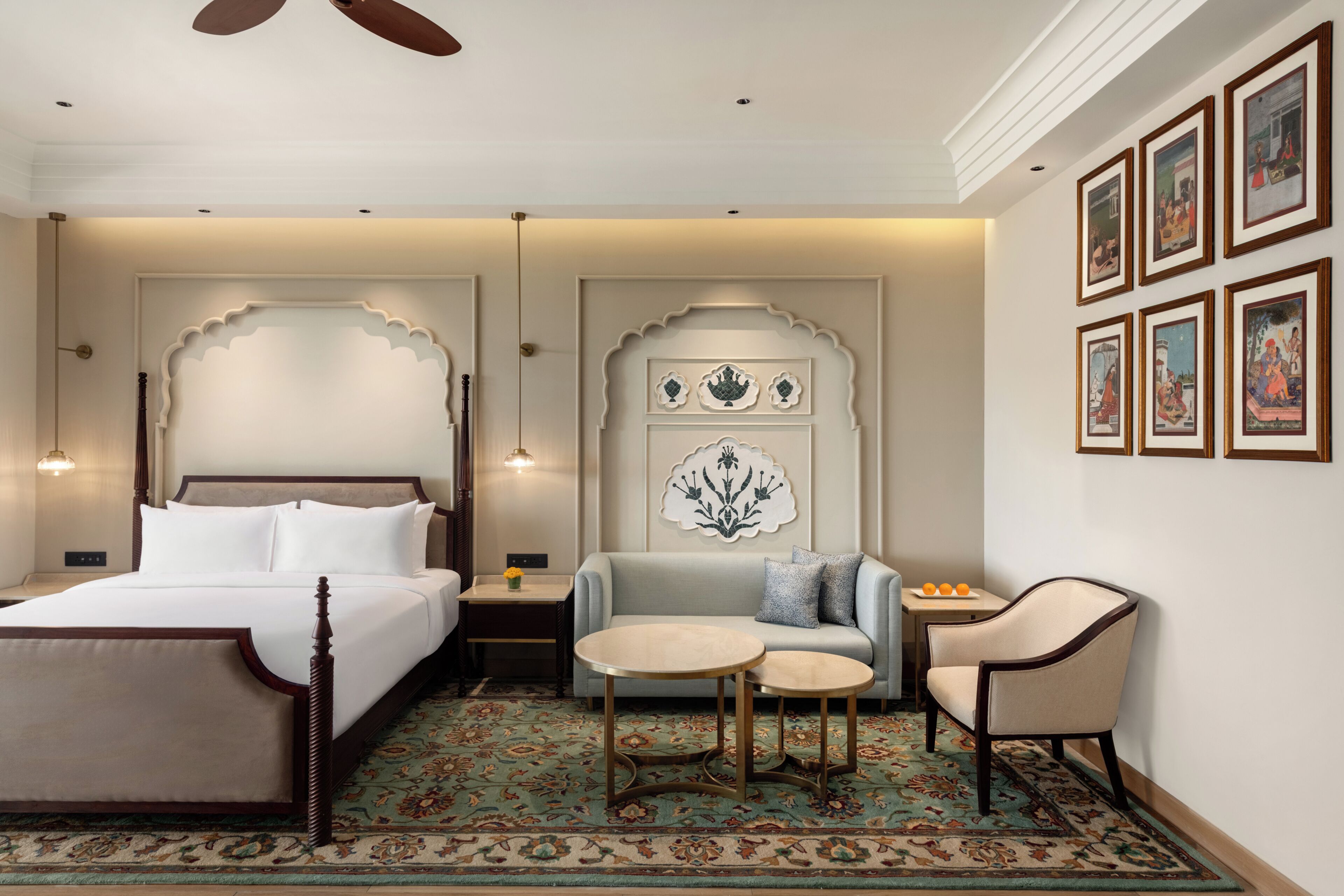 A hotel room with a bed, a sofa, a chair, a small table, and a decorative wall piece.