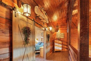 L’intérieur d’un chalet en bois comprend un lit, un coin repas et une grande tête de cerf fixée au mur.