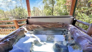 A hot tub with a wooden deck and a view of trees. - Luxury Secluded Lodge with a View | Hot Tub•Games (Logan)