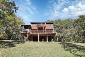 Une cabane en bois à deux étages, dotée d’un balcon et entourée d’arbres.