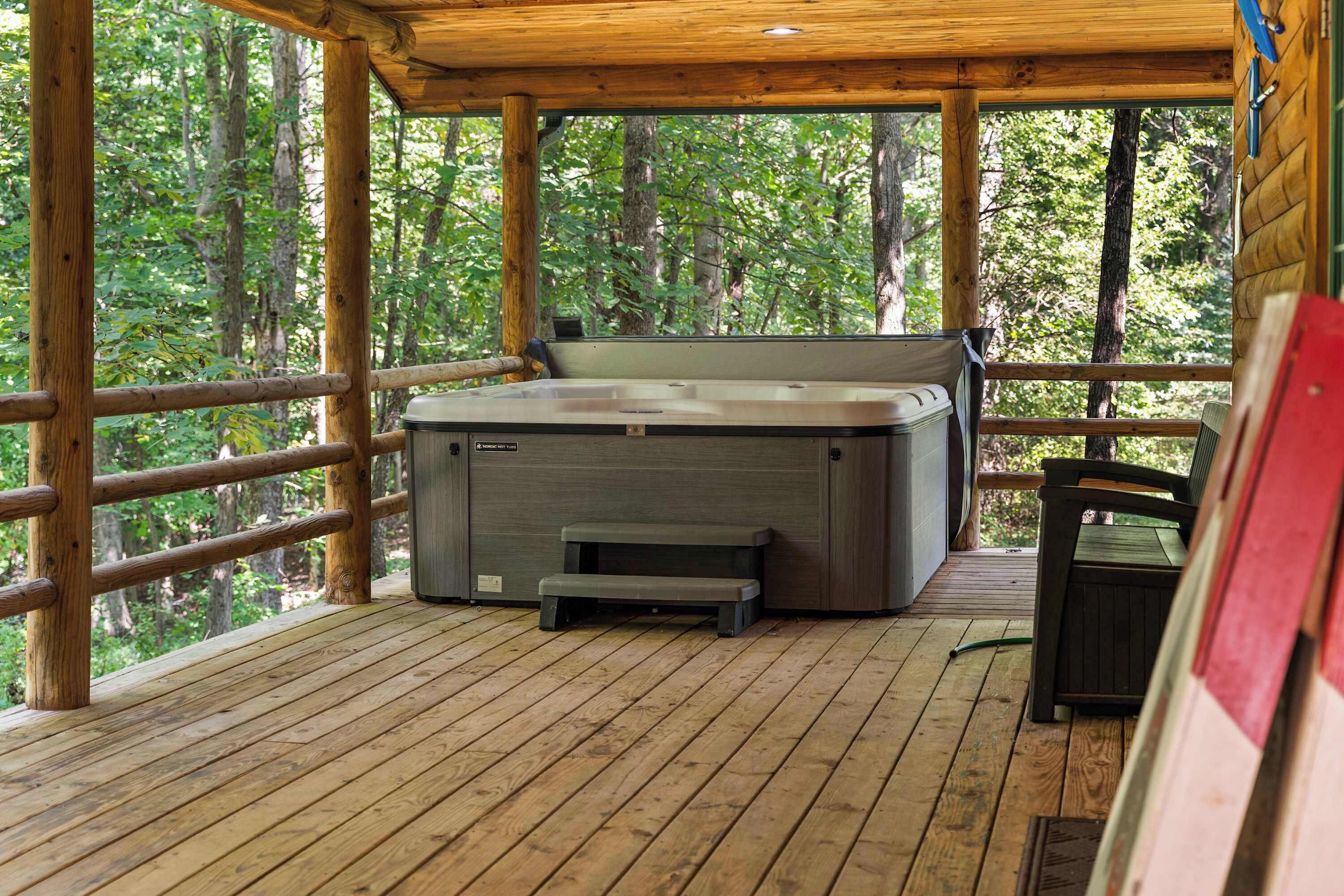 Ein Whirlpool auf einer Holzterrasse mit Blick auf einen Wald.