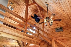 Eine Holzbalkendecke mit freiliegenden Balken, einem Deckenventilator und hängenden Leuchten.
