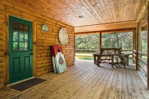 Eine Holzhütte mit einer grünen Tür, einer Wanduhr und einem Picknicktisch vor der Tür.