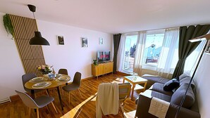 Una sala de estar moderna con comedor, un sofá y un televisor.