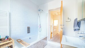 Un baño moderno con una bañera blanca, ducha y lavamanos.