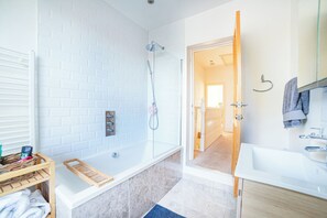 Un baño moderno con una bañera blanca, ducha y lavamanos.
