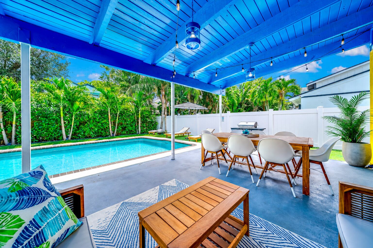 A covered outdoor area with a pool, seating, and a barbecue grill.