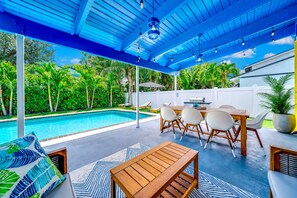 A covered outdoor area with a pool, seating, and a barbecue grill.