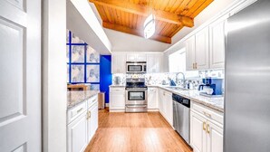 A modern kitchen with white cabinets, stainless steel appliances, and a wooden ceiling. - Sunset Haven w/ Saltwater Pool, Arcade Mins to Beach (Delray Beach)