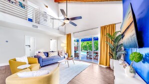 A spacious living area with a sofa, armchair, and a dining table. A ceiling fan is visible, and there is a large window with curtains. - Sunset Haven w/ Saltwater Pool, Arcade Mins to Beach (Delray Beach)
