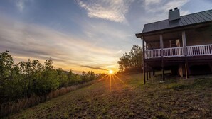 Een huis met een veranda en uitzicht op de zonsondergang.