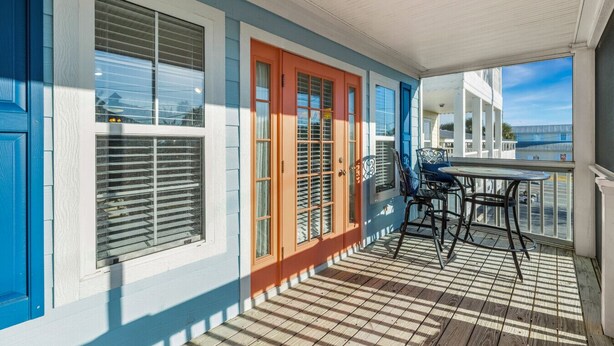A covered porch with a table and chairs, a wooden floor, and a view of the ocean. - Blue Bungalow on 1st! (Cedar Key)