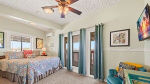 Una camera da letto con un letto, un comodino, una lampada, una ventola a soffitto e vista sull'esterno tramite una porta scorrevole.