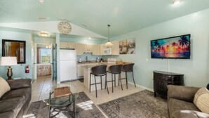 A modern kitchen with a central island, bar stools, and a flat-screen TV on the wall. - Lucky Catch on 1 Street (Cedar Key)