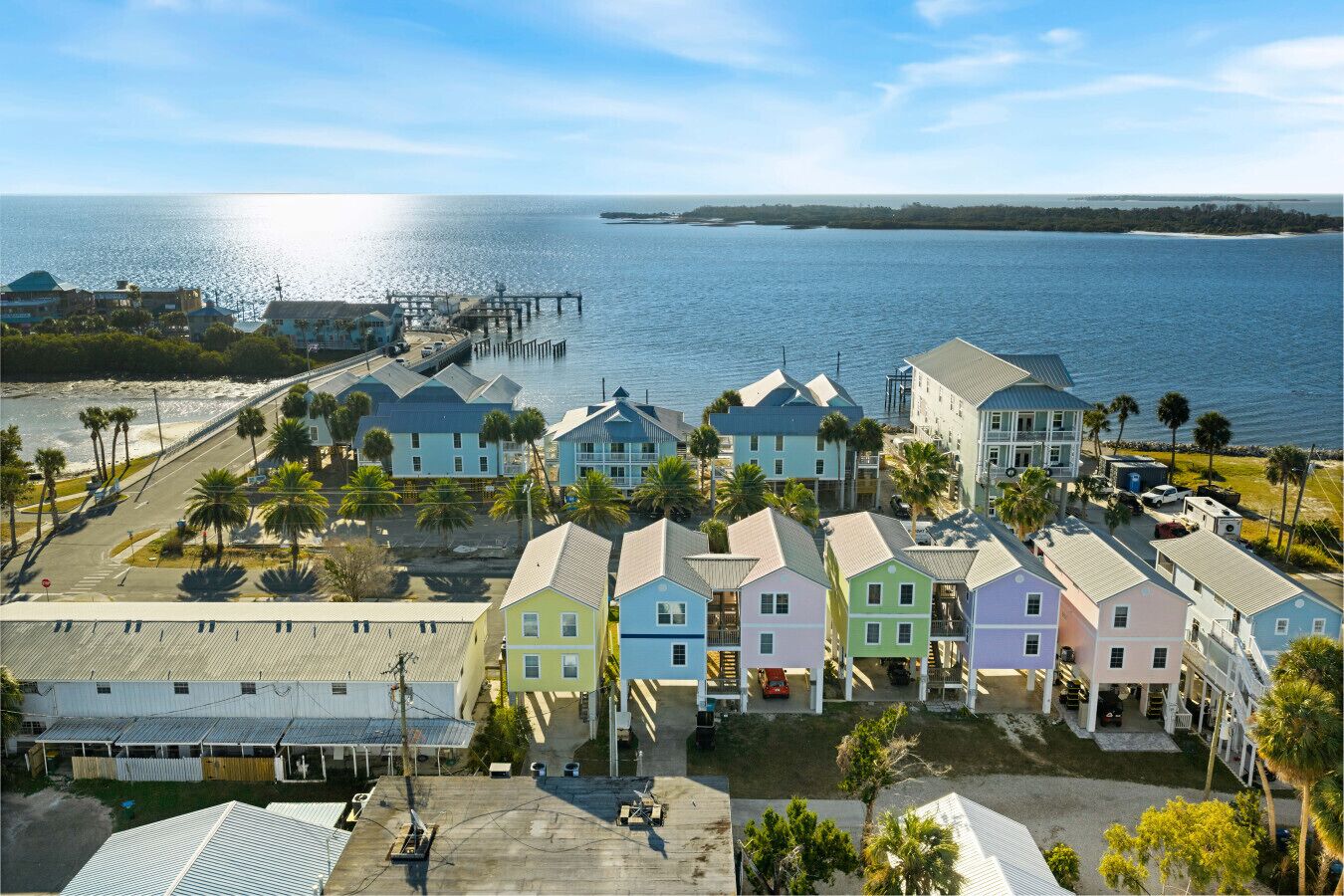 A coastal residential area with colorful houses, a pier, and a view of the ocean.