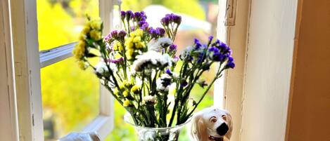 A window sill with a clear vase containing flowers and two dog figurines.