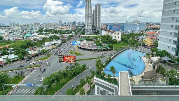 A cityscape with a prominent swimming pool surrounded by greenery and modern buildings. - Sunrise City Premium Urban Residence (Ho Chi Minh City)