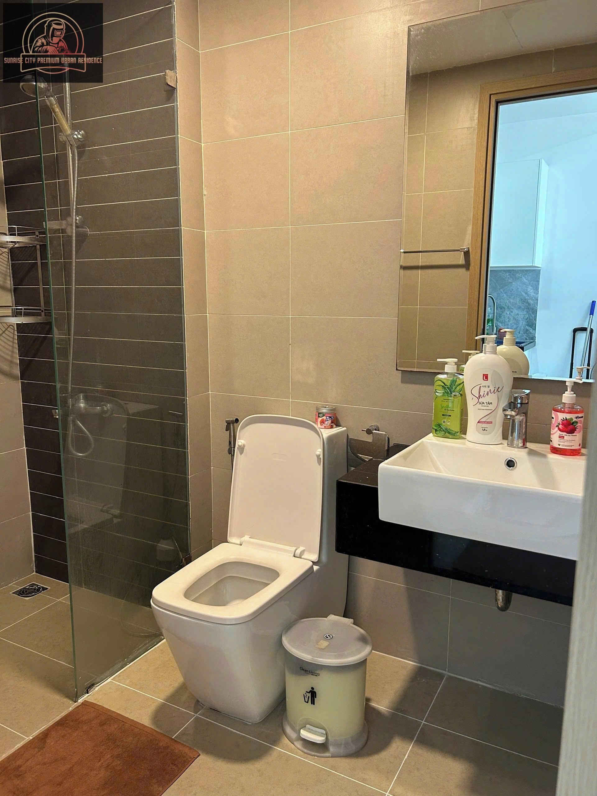 Un bagno moderno con doccia vetrata, un water bianco e un lavandino con articoli da toilette.