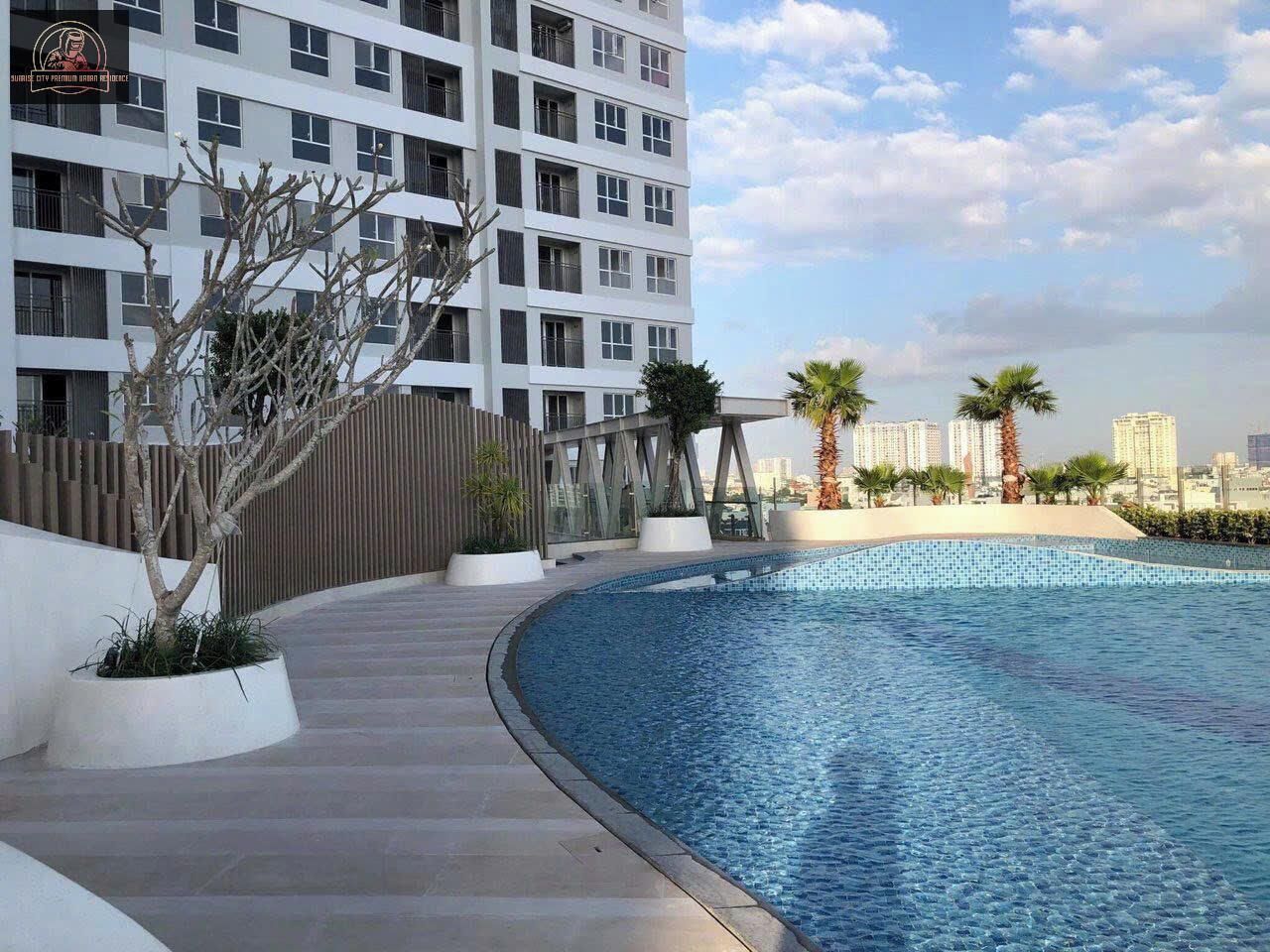 Un hotel moderno con piscina en la azotea, rodeado de palmeras y vistas a la ciudad.