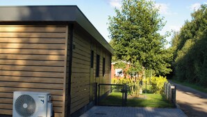 A building with a brick pathway leading to a gated entrance, surrounded by greenery and trees. - Vacation cottage Noa (Twist)