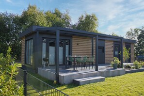 Une maison moderne dotée d’un patio couvert, d’un barbecue et d’un petit jardin.