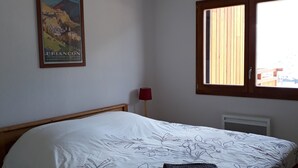Ein Schlafzimmer mit einem Bett, einem Bild an der Wand, einem Fenster und einer roten Lampe.