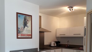 Eine moderne Küche mit weißen Schränken, einer grauen Arbeitsplatte und zwei hölzernen Barhocker.