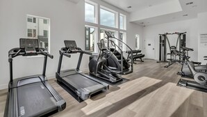 Ein modernes Fitnessstudio mit Laufbändern, Crosstrainern und Krafttrainingsgeräten.
