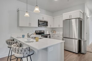 A modern kitchen with white cabinetry, stainless steel appliances, and pendant lighting. - Bright 3BR Home in Quiet Community • Pool & Fitness Center (Spanish Fork)
