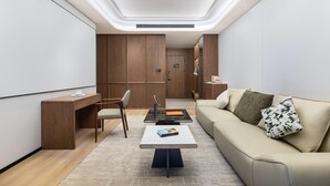A modern living room with a sofa, coffee table, and a desk with a chair. - Hawthorn By Wyndham Chuxiong Yuanmou (Chuxiong Yi)