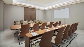 A conference room with a long table, multiple chairs, water bottles, and a projector screen. - Hawthorn By Wyndham Chuxiong Yuanmou (Chuxiong Yi)