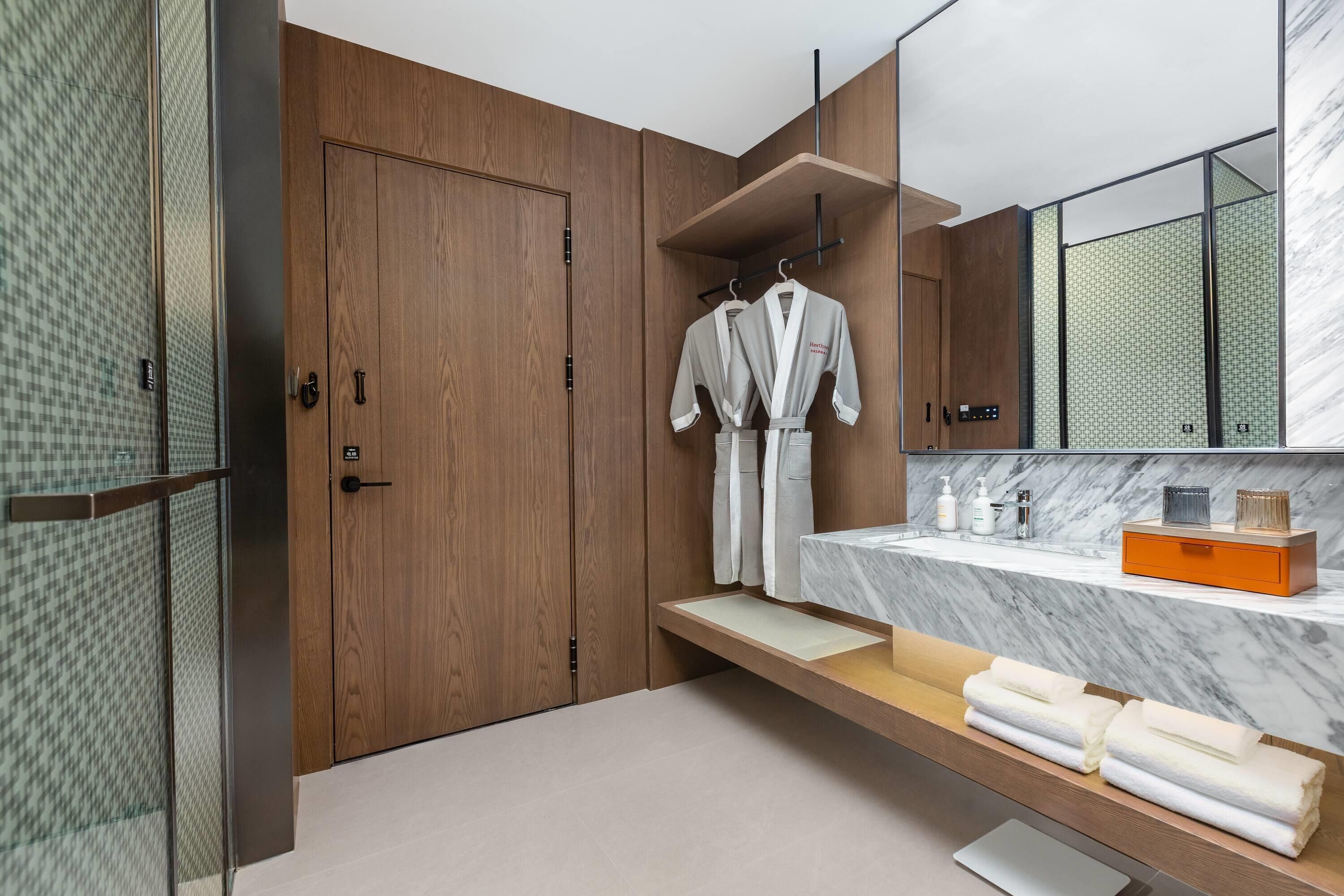 A modern bathroom with wooden cabinets, a marble countertop, and a large mirror.