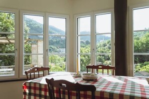 Ein Essbereich mit Tisch für zwei Personen, große Fenster mit Blick auf eine Berglandschaft.